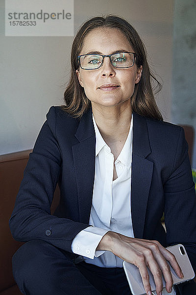 Porträt einer selbstbewussten Geschäftsfrau mit Handy und Brille