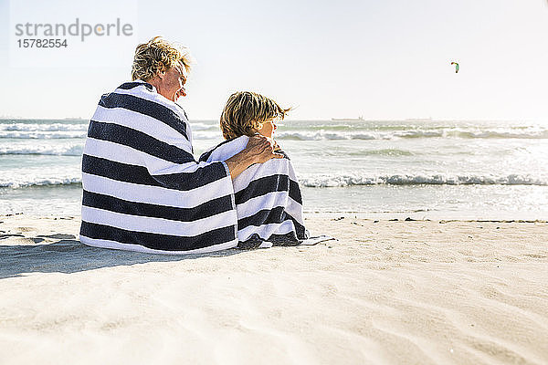 Vater mit Sohn in ein Handtuch gewickelt am Strand