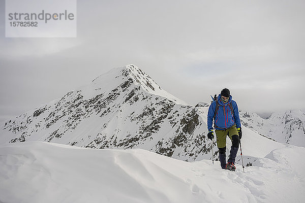Mann auf einer Exkursion auf dem Kamm eines schneebedeckten Berges  Lombardei  Veltlin  Italien