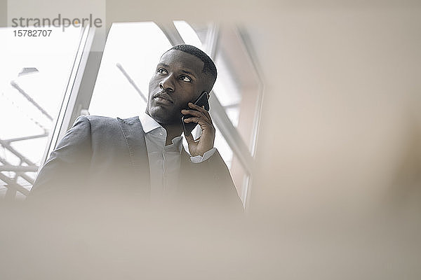 Porträt eines jungen Geschäftsmannes vor dem Fenster am Telefon