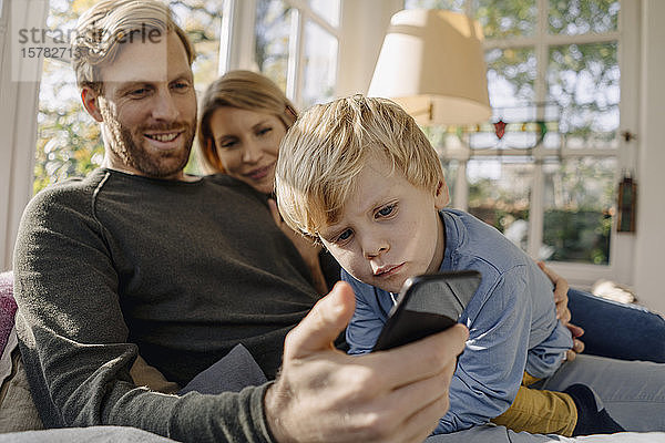 Glückliche Familie benutzt Mobiltelefon im Wintergarten zu Hause
