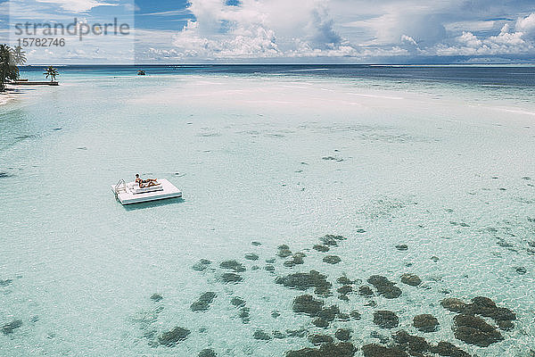 Auf einer Plattform im Meer liegendes Ehepaar  Insel Maguhdhuvaa  Gaafu-Dhaalu-Atoll  Malediven