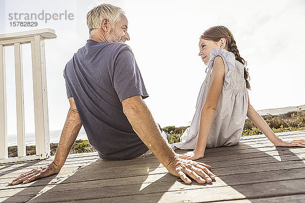 Vater und Tochter sitzen bei Sonnenschein auf der Terrasse