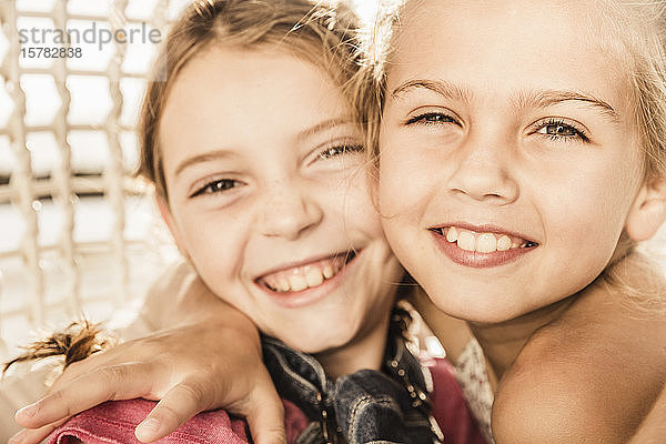 Porträt von zwei fröhlich-süßen Mädchen  die sich umarmen