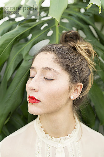 Porträt einer jungen Frau mit roten Lippen und entspannt geschlossenen Augen