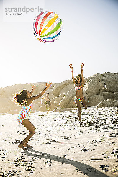 Glückliche Mutter spielt mit Tochter mit aufblasbarem Ball am Strand
