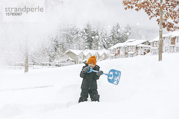 Lachender kleiner Junge schaufelt Schnee  Vancouver  Kanada