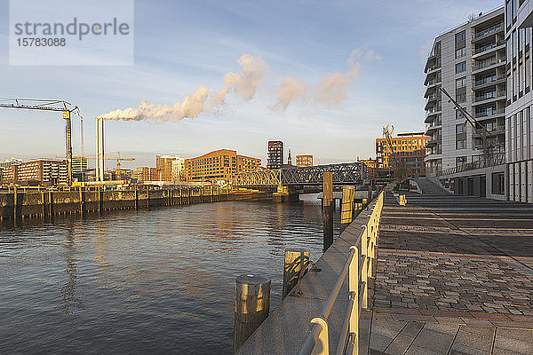 Deutschland  Hamburg  HafenCity-Hafen im Morgengrauen mit Rauch aus Industrieschornsteinen im Hintergrund