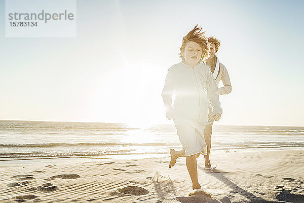 Vater amüsiert sich mit seinem Sohn am Strand  rennt im Sand