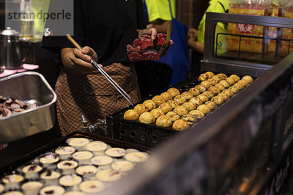Japan  Osaka  Frau kocht Takoyaki am Straßenstand
