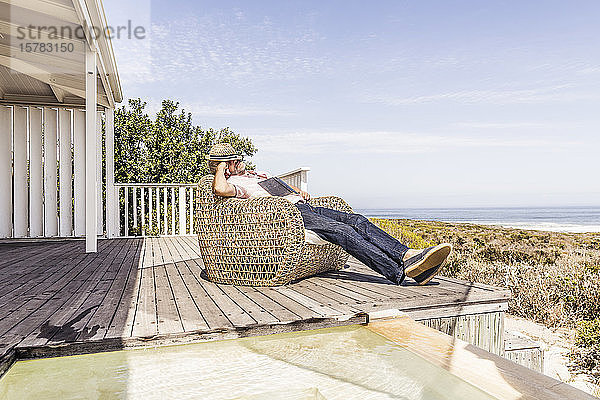 Mann schlief beim Lesen eines Buches auf einem Deck an der Küste ein