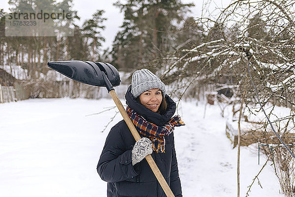 Porträt einer lächelnden Frau mit Schneeschaufel