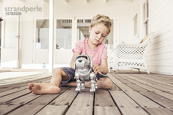 Junge spielt mit Roboterhund auf der Veranda