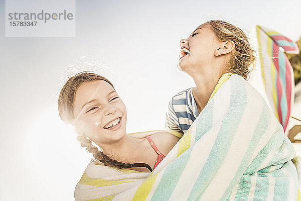 Zwei lachende niedliche Mädchen in ein Handtuch gewickelt