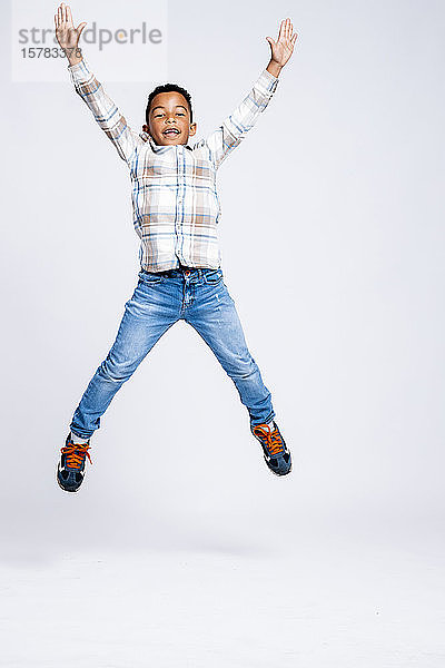 Porträt eines in die Luft springenden Jungen vor weißem Hintergrund
