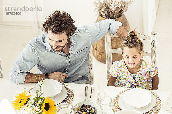 Vater und Tochter sitzen am Esstisch