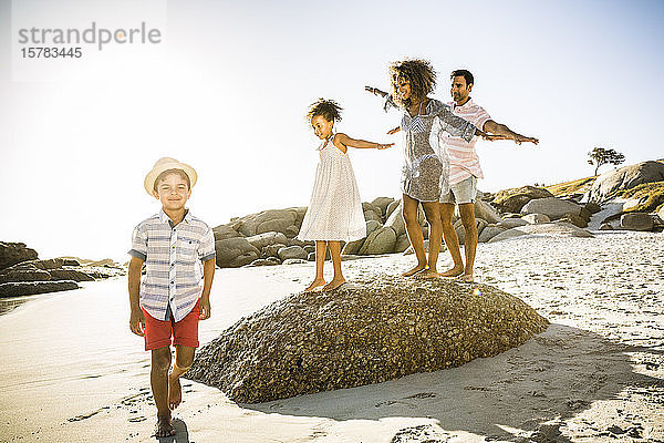 Glückliche Familie balanciert auf einem Felsen am Strand