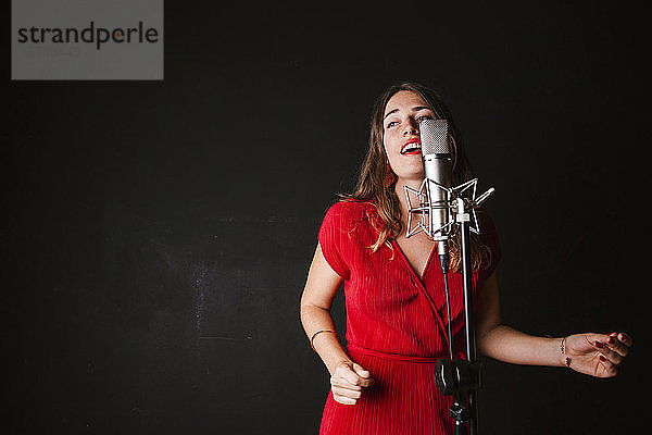 Porträt einer Sängerin mit Mikrofon  in rotem Kleid