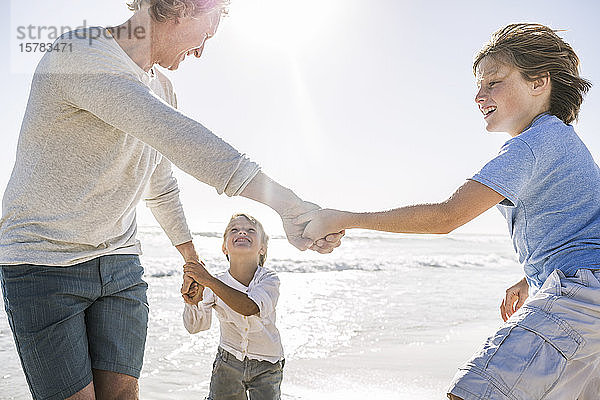 Vater amüsiert sich mit seinem Sohn am Strand  hält Händchen