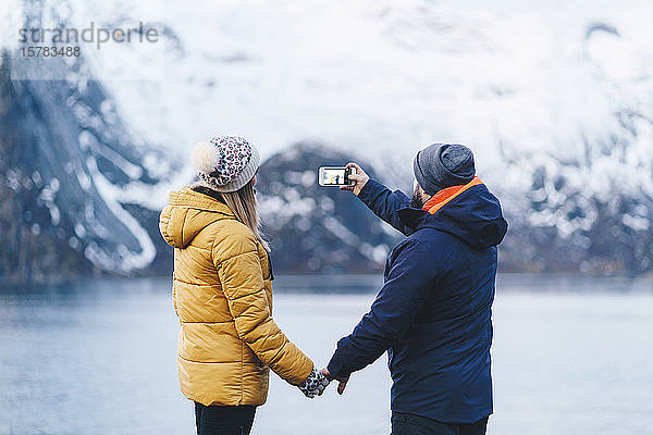 Touristenpaar beim Fotografieren mit einem Smartphone auf Hamnoy  Lofoten  Norwegen