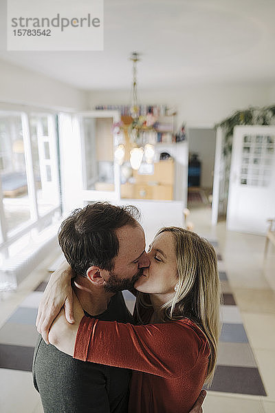 Glückliches Paar umarmt und küsst sich in ihrem gemütlichen Heim