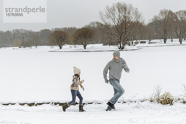 Vater und Tochter laufen in Winterlandschaft