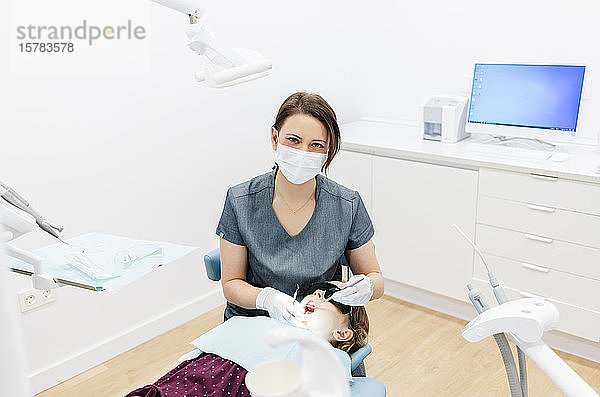 Porträt eines Zahnarztes  der ein Mädchen untersucht