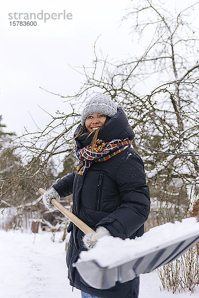 Porträt einer lächelnden Frau mit Schneeschaufel