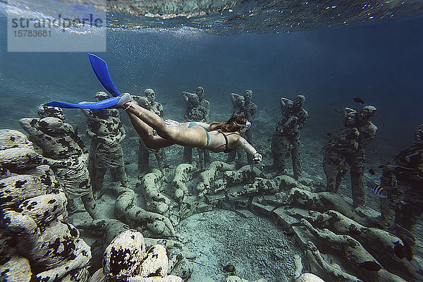 Frau schwimmt in der Nähe einer Unterwasser-Skulptur von Jason deCaires Taylor  Insel Gili Meno  Bali  Indonesien