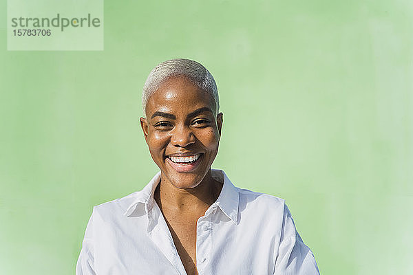 Porträt einer lachenden Frau vor grüner Wand