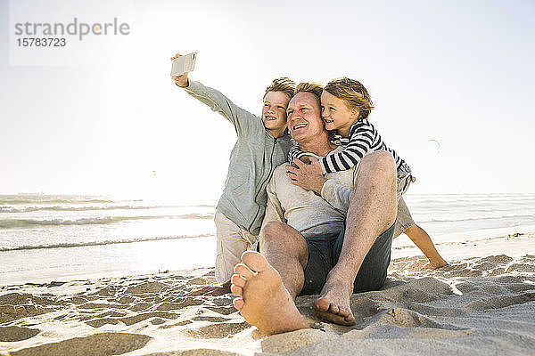 Junge mit Bruder und Vater beim Selbermachen am Strand