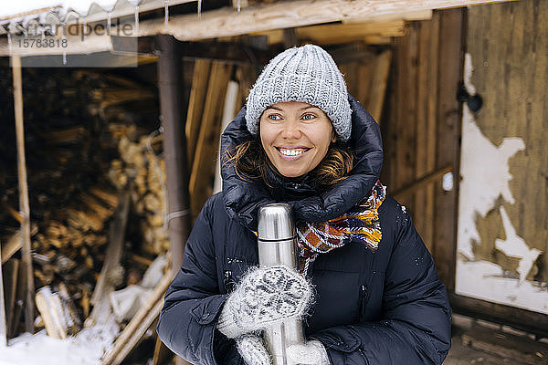 Porträt einer glücklichen Frau mit Thermoskanne im Winter