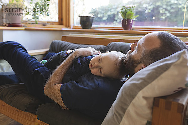 Vater und Sohn schlafen zusammen auf dem Sofa