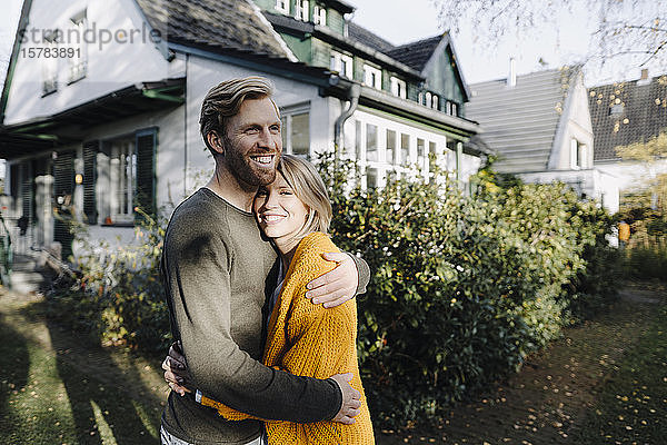 Glückliches Paar umarmt sich vor ihrem Haus