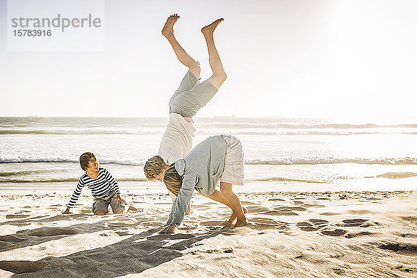 Vater amüsiert sich mit seinem Sohn am Strand  übt