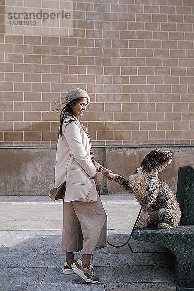 Junge Frau mit ihrem Hund in der Stadt beim Pfötchengeben