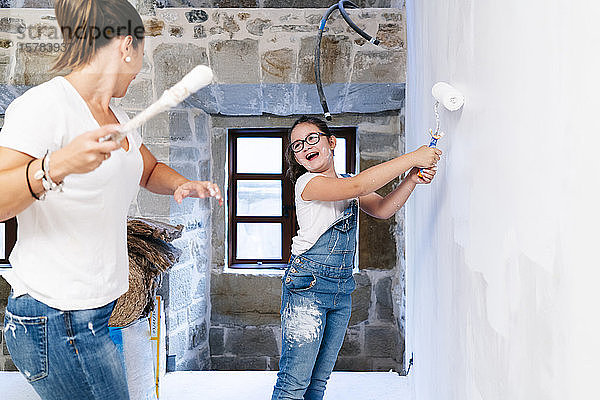 Mutter und Tochter amüsieren sich beim Streichen einer Wand ihres neuen Hauses