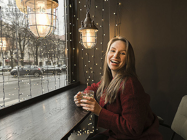 Porträt einer lachenden jungen Frau mit einer Tasse Tee in einem Café