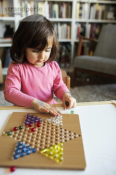 Kleines Mädchen spielt mit Murmeln auf dem Tisch