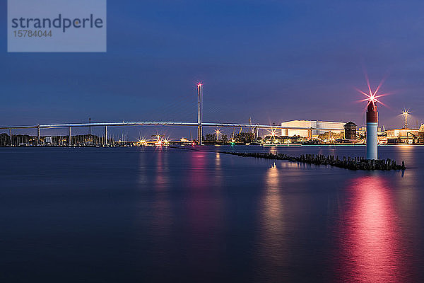 Deutschland  Mecklenburg-Vorpommern  Stralsund  Leuchtturm am Ende des Pfeilers in der Abenddämmerung mit der Rügenbrücke im Hintergrund