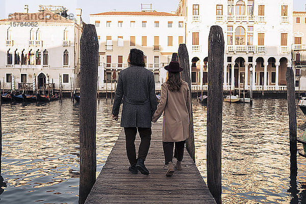 Rückansicht eines jungen Paares beim Spaziergang auf einem Steg am Canal Grande in Venedig  Italien