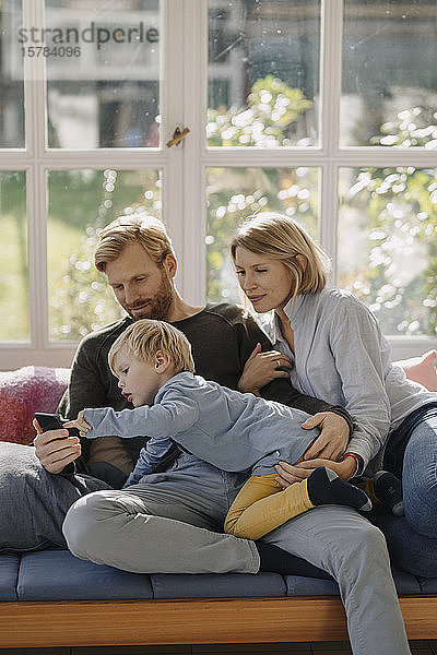 Familie benutzt Mobiltelefon im Wintergarten zu Hause