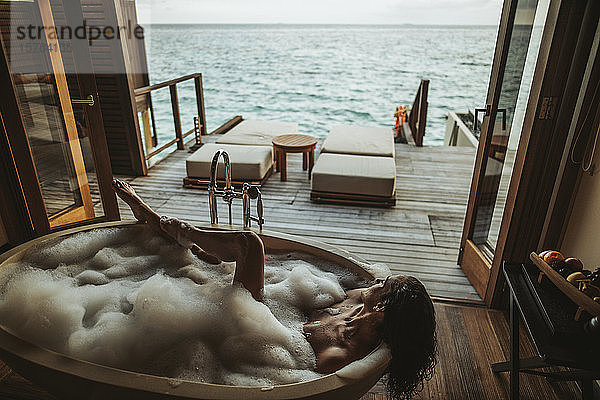 Frau entspannt sich in Badewanne mit Blick auf das Meer  Insel Maguhdhuvaa  Gaafu-Dhaalu-Atoll  Malediven