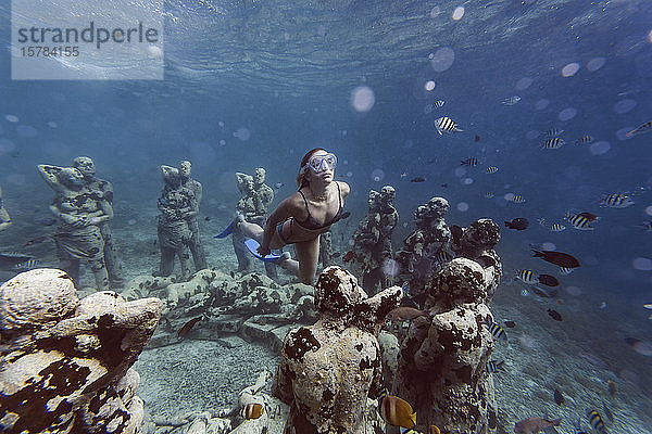 Frau schwimmt in der Nähe einer Unterwasser-Skulptur von Jason deCaires Taylor  Insel Gili Meno  Bali  Indonesien