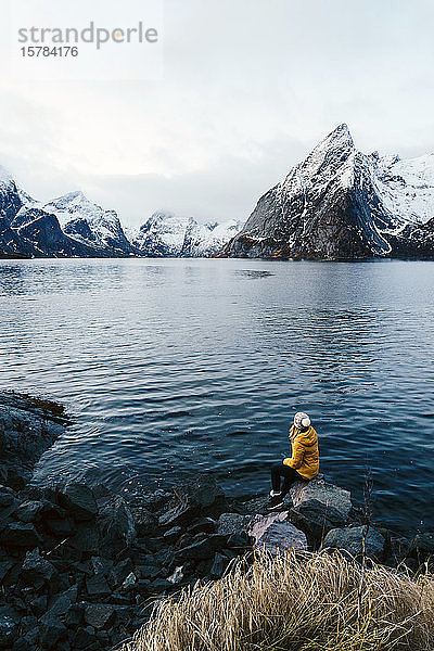 Tourist sitzt auf einem Felsen und genießt die Aussicht auf Hamnoy  Lofoten  Norwegen