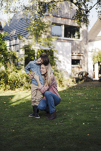 Mutter umarmt Sohn im Garten ihres Hauses