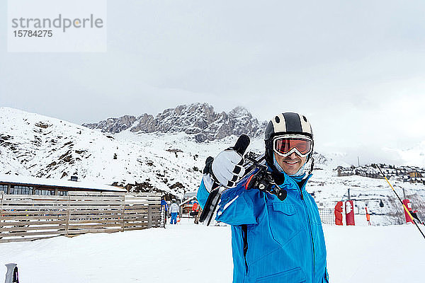 Porträt eines lächelnden Mannes mit Skiern im Skigebiet