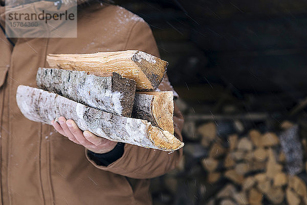 Männerhand hält Brennholz im Winter  Nahaufnahme
