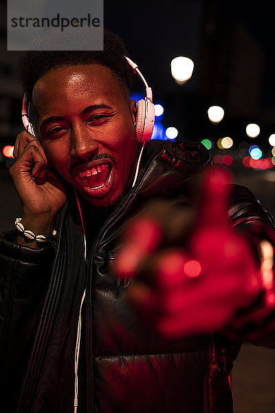 Porträt eines Mannes in der Stadt bei Nacht mit Kopfhörern