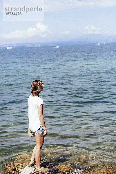 Junge Frau steht am Seeufer  Gardasee  Italien